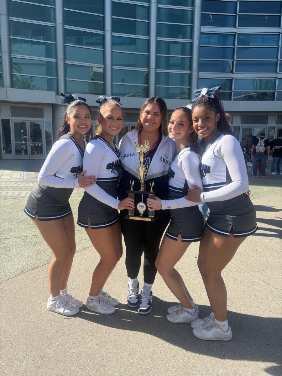 Coach Leilani taking a photo at a competition with the cheerleaders from Shadow