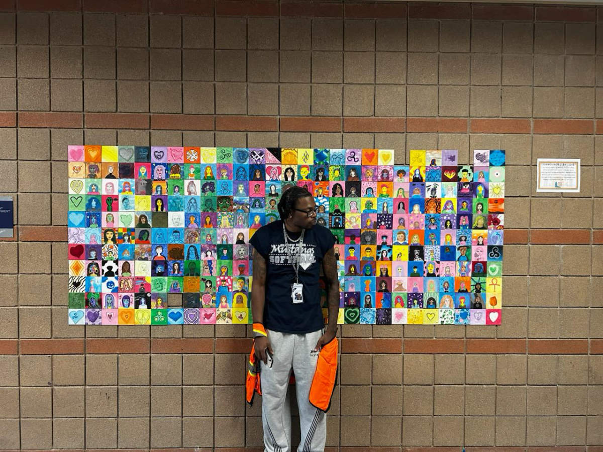Hall monitor posed in front of mural made by Shadow Ridge art students