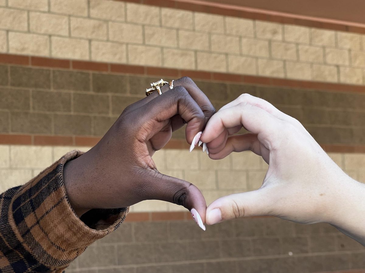 Two students making a heart to resemble kindness. 