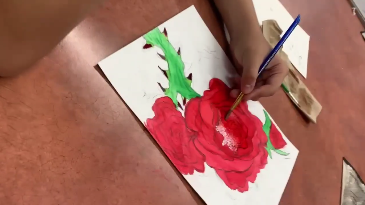 Student painting a rose at art club