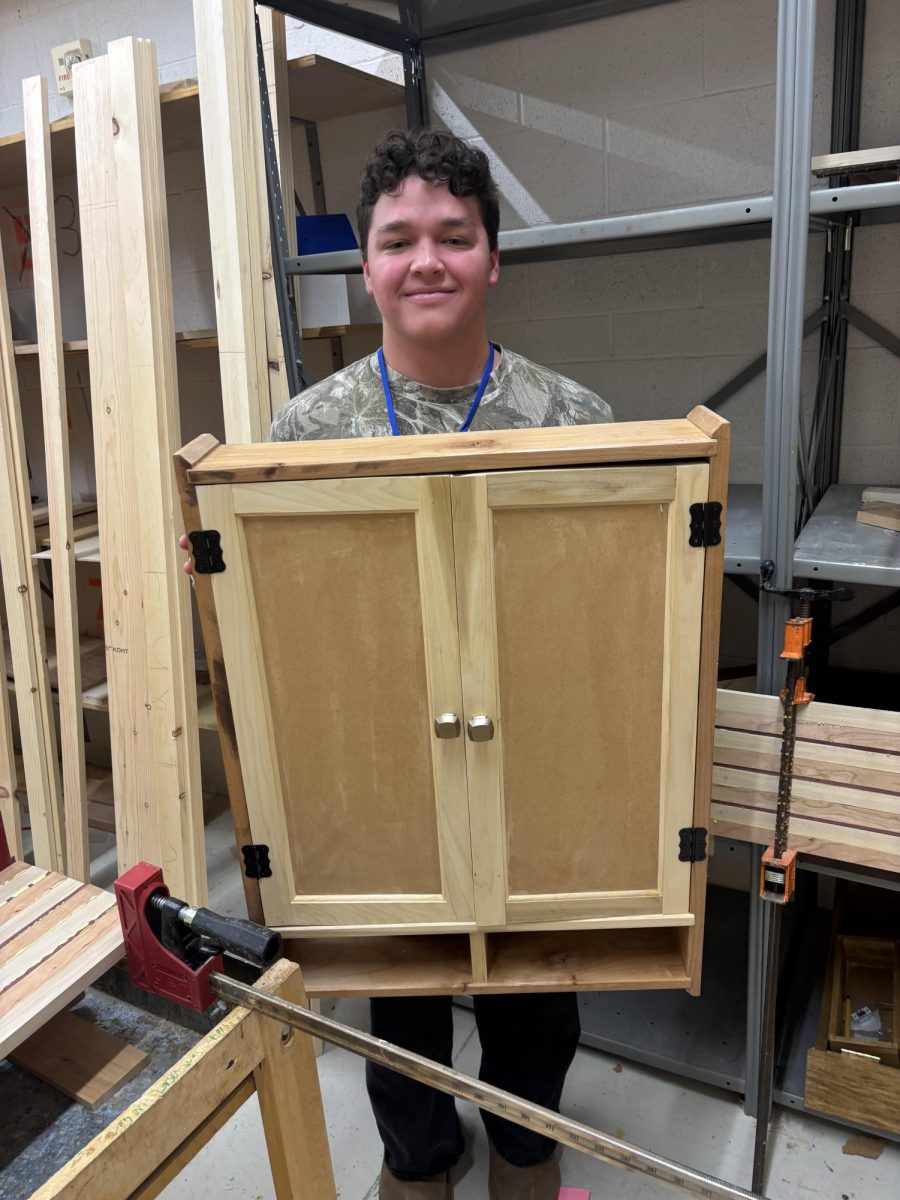 Nathan holding up dartboard cabinet.