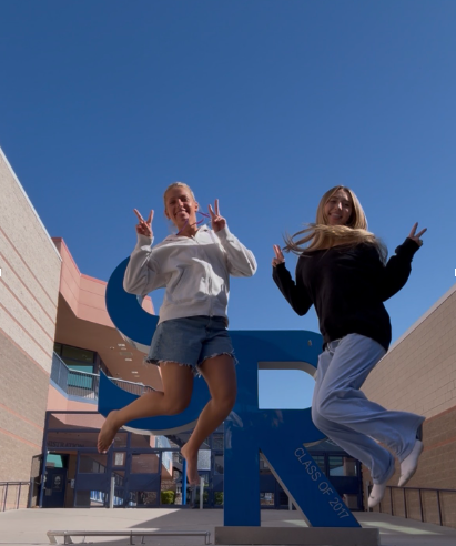 Students Chesnie Hoge and Sophie Finlinson jumping in front of the school's SR statue