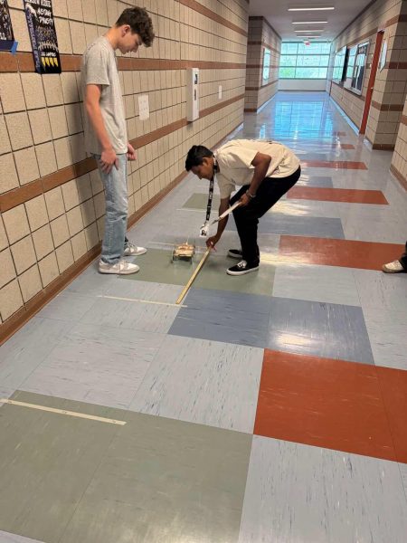 Mr. Payne helps student measure out distance.